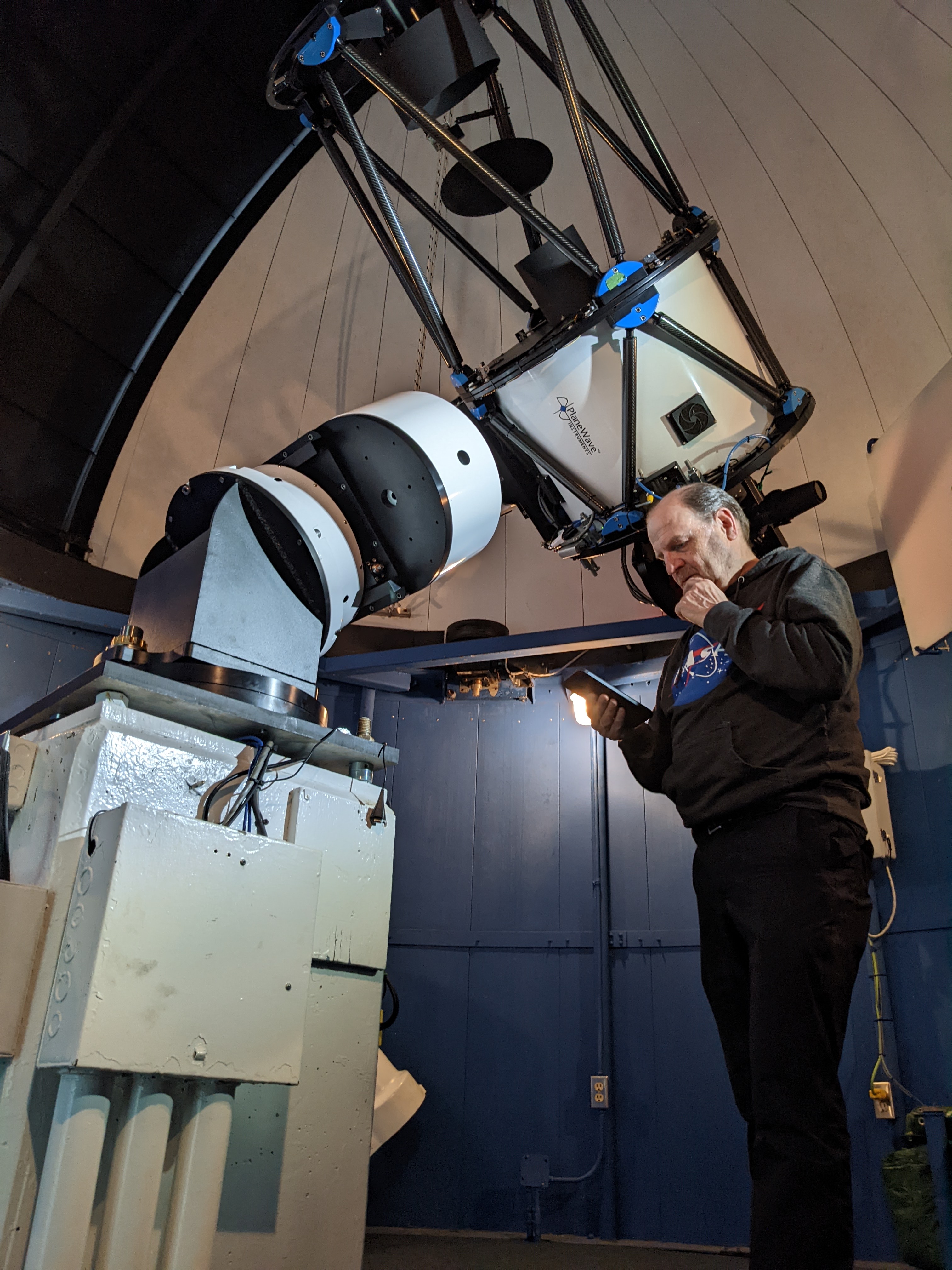 Image from inside the BGO dome, Dave is looking at his phone while standing underneath the telescope.